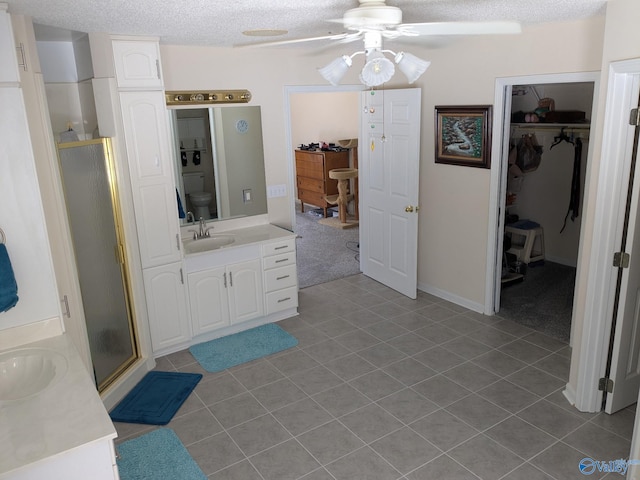 full bathroom featuring a textured ceiling, a shower stall, vanity, and tile patterned floors