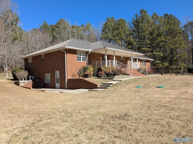 back of house featuring metal roof, a lawn, and brick siding