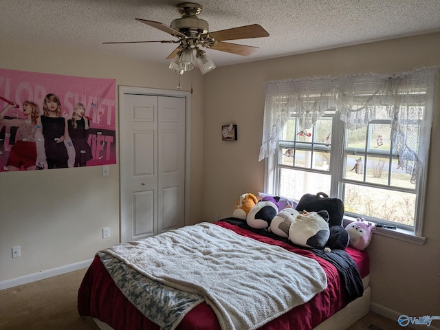 carpeted bedroom featuring ceiling fan, a closet, baseboards, and a textured ceiling