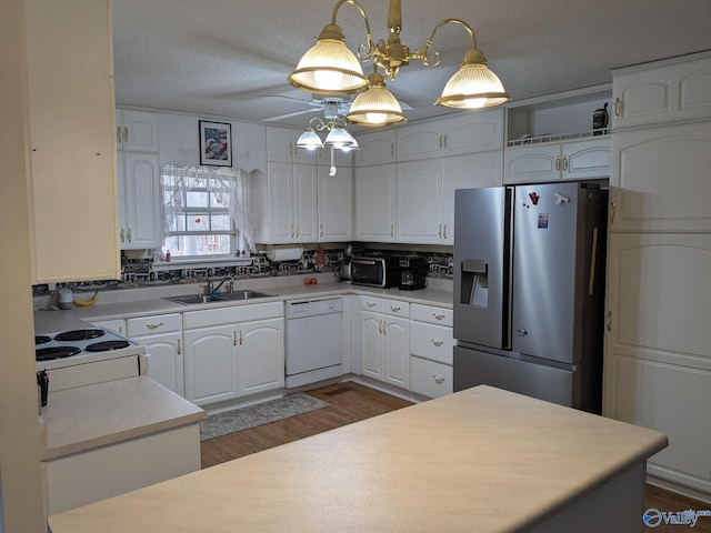 kitchen with white appliances, white cabinets, a sink, and a textured ceiling