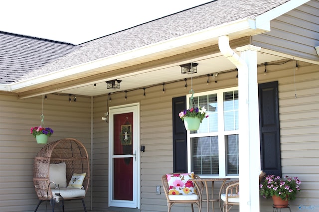 doorway to property with roof with shingles and covered porch