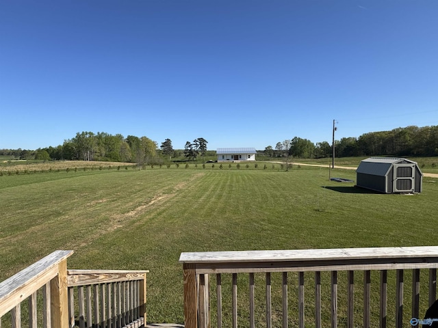 view of yard featuring an outdoor structure, a storage shed, and a rural view