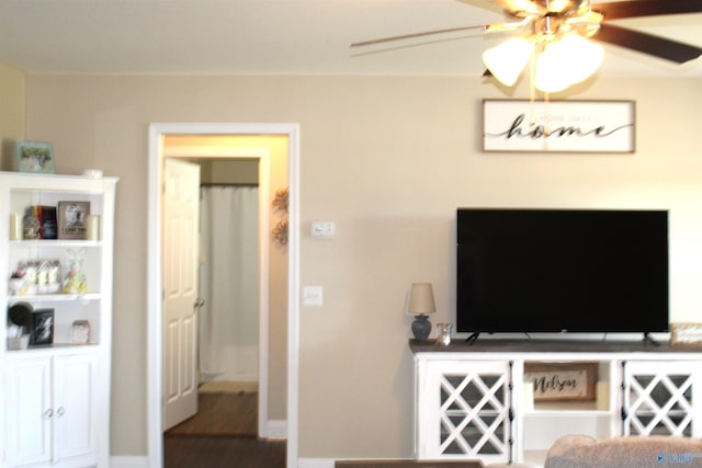 living room with ceiling fan, baseboards, and wood finished floors