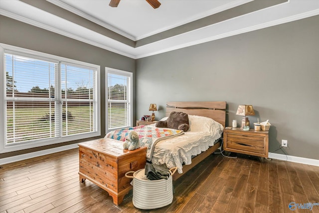 bedroom with crown molding, a tray ceiling, and dark wood finished floors