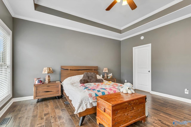 bedroom featuring dark wood-style floors, crown molding, a raised ceiling, visible vents, and baseboards