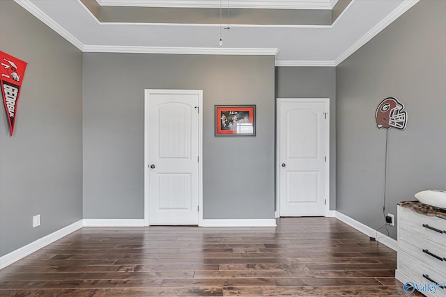 unfurnished bedroom featuring ornamental molding, a raised ceiling, dark wood-type flooring, and baseboards