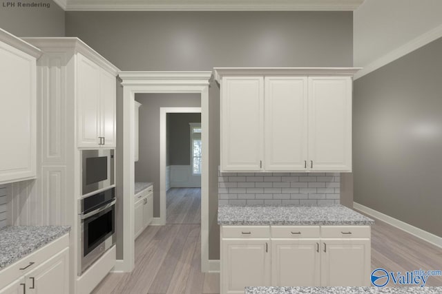 kitchen featuring light stone countertops, stainless steel oven, and white cabinets