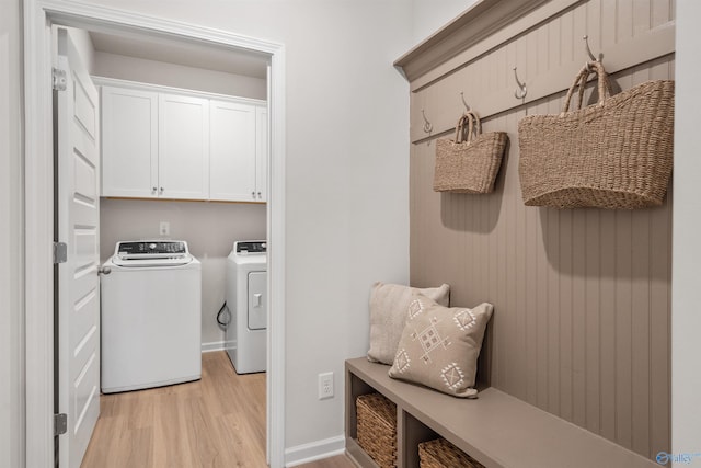 laundry room featuring light hardwood / wood-style floors, cabinets, and washing machine and clothes dryer