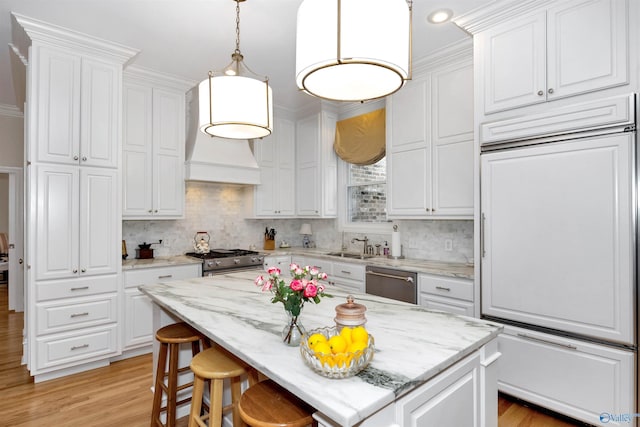 kitchen featuring light stone counters, high quality appliances, a kitchen island, and white cabinets