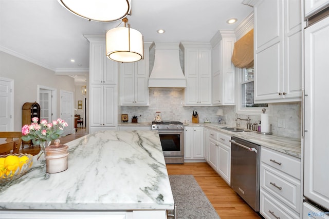 kitchen featuring decorative light fixtures, sink, white cabinets, custom exhaust hood, and stainless steel appliances