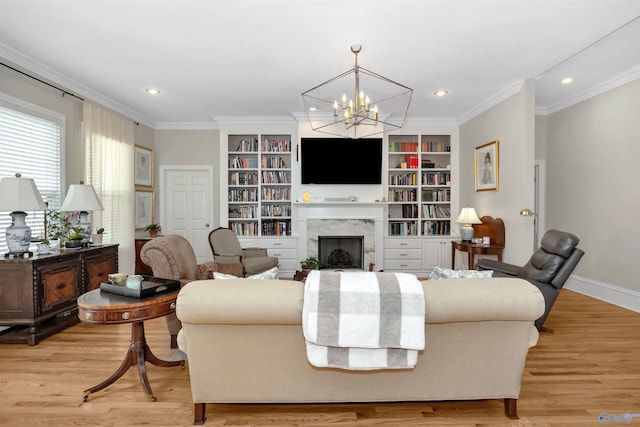 living room with ornamental molding, an inviting chandelier, a high end fireplace, and light hardwood / wood-style flooring