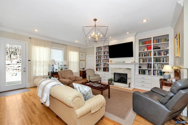 living room with a notable chandelier, crown molding, a fireplace, and light hardwood / wood-style floors