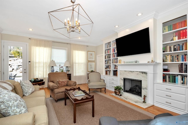 living room featuring crown molding, built in features, a premium fireplace, and hardwood / wood-style flooring