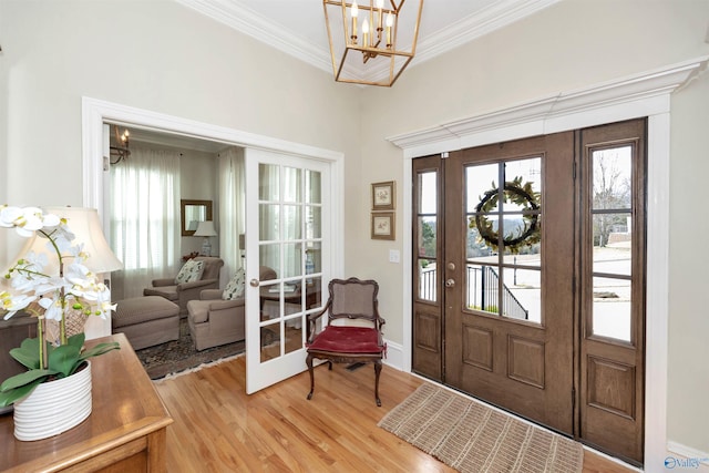 foyer entrance featuring crown molding, light hardwood / wood-style flooring, french doors, and a chandelier