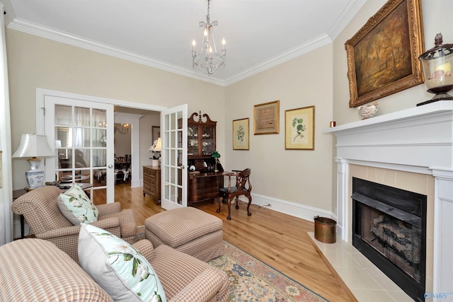 living room with an inviting chandelier, ornamental molding, french doors, and light wood-type flooring