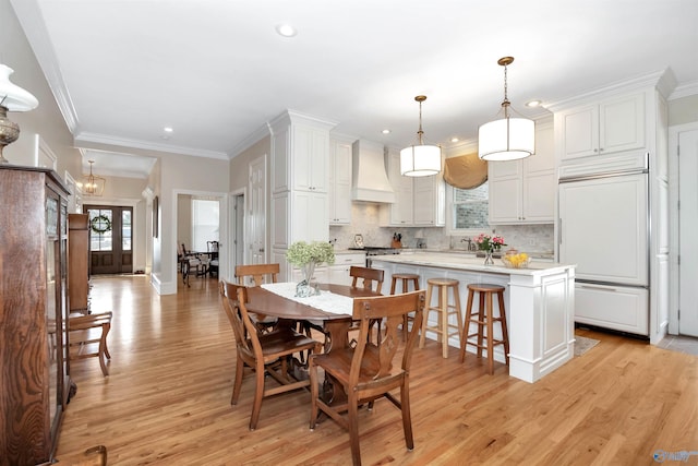 dining room with light hardwood / wood-style flooring, ornamental molding, and french doors