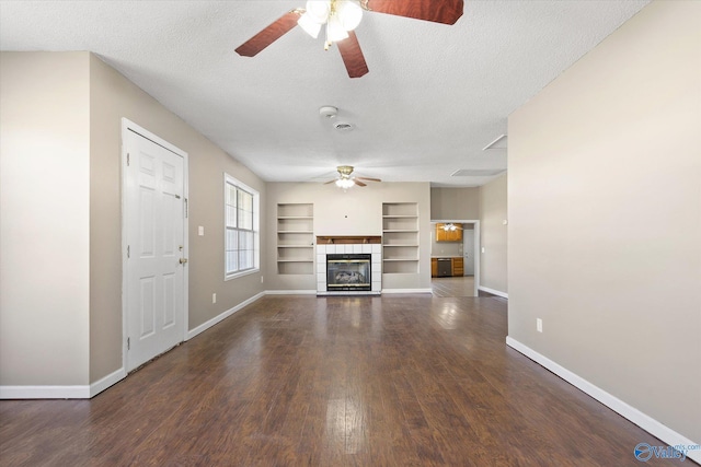 unfurnished living room with a tiled fireplace, dark hardwood / wood-style flooring, and a textured ceiling