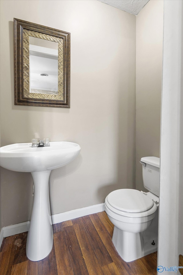 bathroom featuring wood-type flooring, toilet, and sink