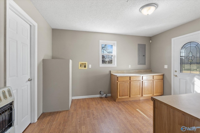 laundry room featuring a textured ceiling, electric panel, heating unit, and light hardwood / wood-style flooring