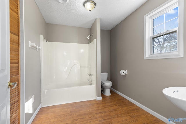 bathroom with shower / bathing tub combination, a textured ceiling, hardwood / wood-style flooring, and toilet