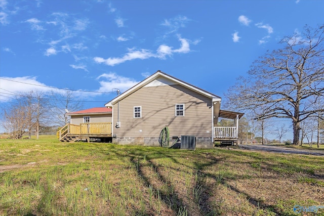 rear view of house featuring a wooden deck and a yard