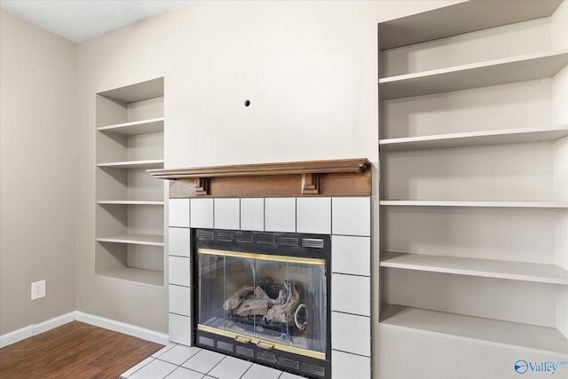 unfurnished living room with hardwood / wood-style flooring and a tiled fireplace