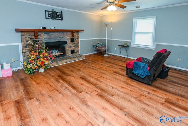 sitting room with ornamental molding, a brick fireplace, hardwood / wood-style flooring, and ceiling fan