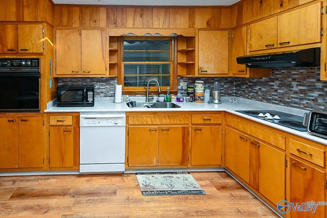 kitchen with black appliances, sink, light wood-type flooring, and decorative backsplash