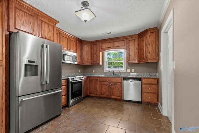 kitchen featuring brown cabinetry, visible vents, appliances with stainless steel finishes, and a sink
