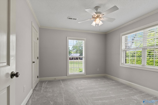 empty room with plenty of natural light, visible vents, light colored carpet, and ornamental molding