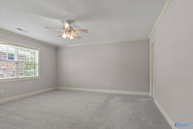 empty room featuring a textured ceiling, visible vents, carpet, ceiling fan, and crown molding