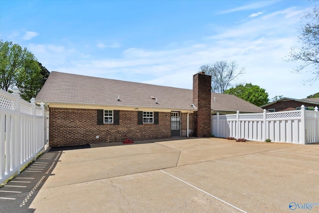 back of property with a patio area, a chimney, a shingled roof, fence, and brick siding