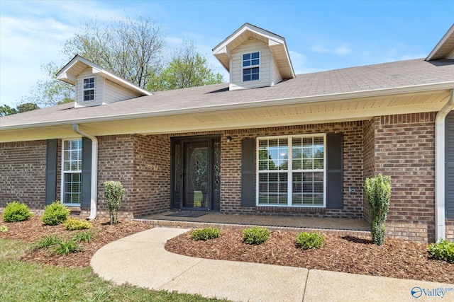 doorway to property with brick siding and a porch
