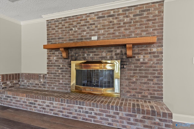 room details featuring a textured ceiling, baseboards, wood finished floors, a brick fireplace, and crown molding