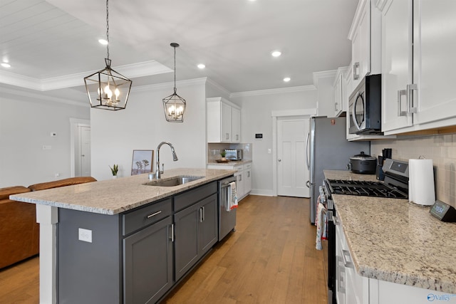 kitchen with sink, appliances with stainless steel finishes, white cabinetry, an island with sink, and decorative light fixtures