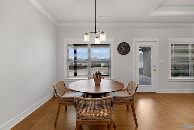 dining area featuring hardwood / wood-style flooring, crown molding, and a chandelier