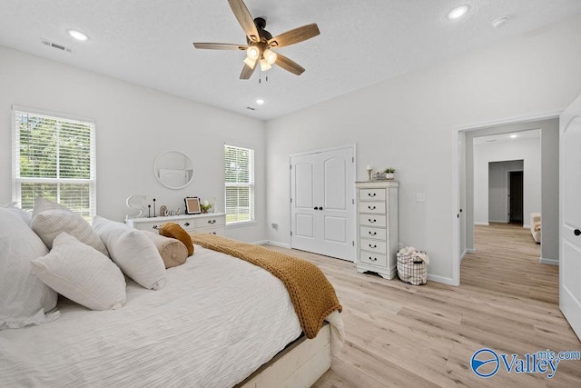 bedroom with ceiling fan, a closet, and light hardwood / wood-style flooring