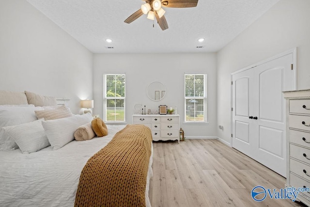 bedroom with a textured ceiling, ceiling fan, and light hardwood / wood-style flooring