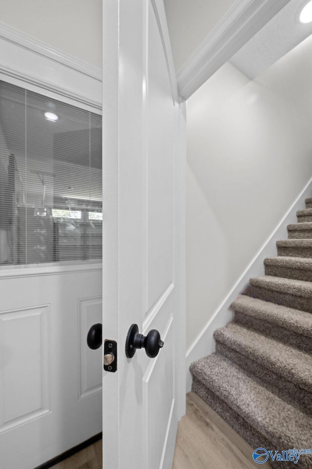 staircase with crown molding and wood-type flooring