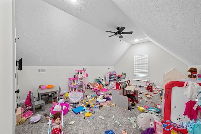 recreation room featuring ceiling fan, vaulted ceiling, and a textured ceiling