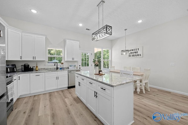 kitchen featuring a center island, light wood-type flooring, dishwasher, pendant lighting, and white cabinets