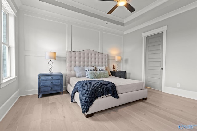 bedroom with a raised ceiling, light wood-type flooring, and ceiling fan