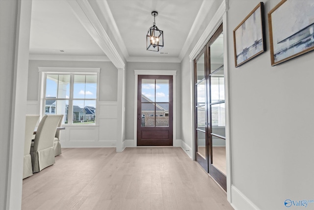 entrance foyer featuring light hardwood / wood-style floors, a notable chandelier, ornamental molding, and plenty of natural light