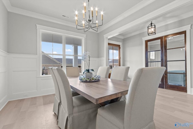 dining space with an inviting chandelier, light hardwood / wood-style floors, and ornamental molding