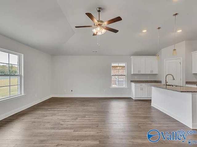 kitchen with dark hardwood / wood-style floors, dark stone counters, sink, decorative light fixtures, and white cabinets