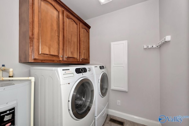 clothes washing area featuring water heater, cabinets, washing machine and dryer, and tile patterned floors