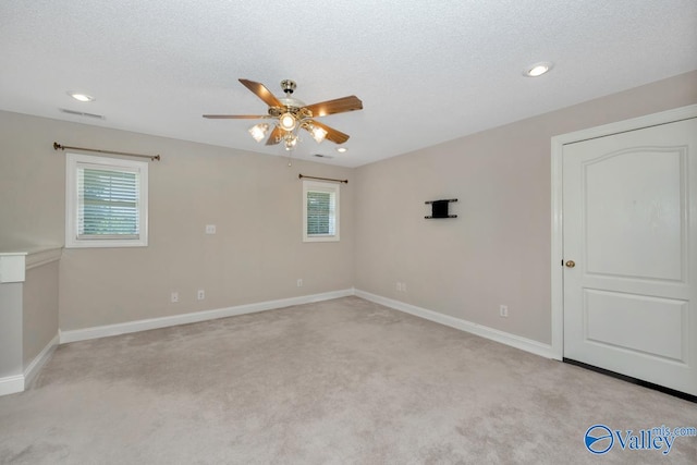 carpeted spare room with a textured ceiling and ceiling fan