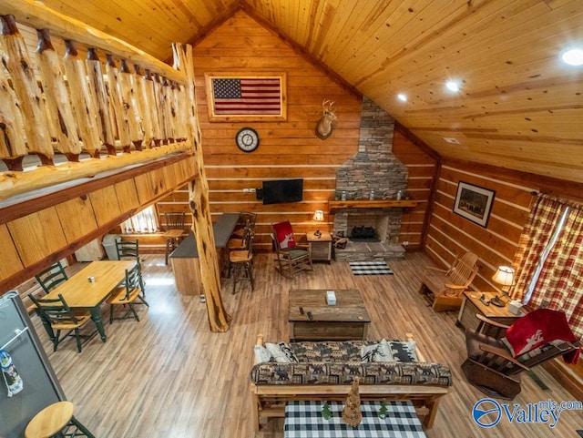 living room with light wood-type flooring, a fireplace, wooden walls, vaulted ceiling, and wood ceiling