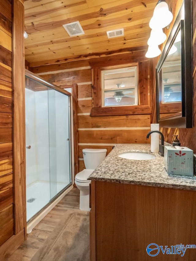 bathroom featuring toilet, vanity, an enclosed shower, wood-type flooring, and wood walls