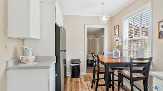 dining area with baseboards, crown molding, a chandelier, and light wood-style flooring